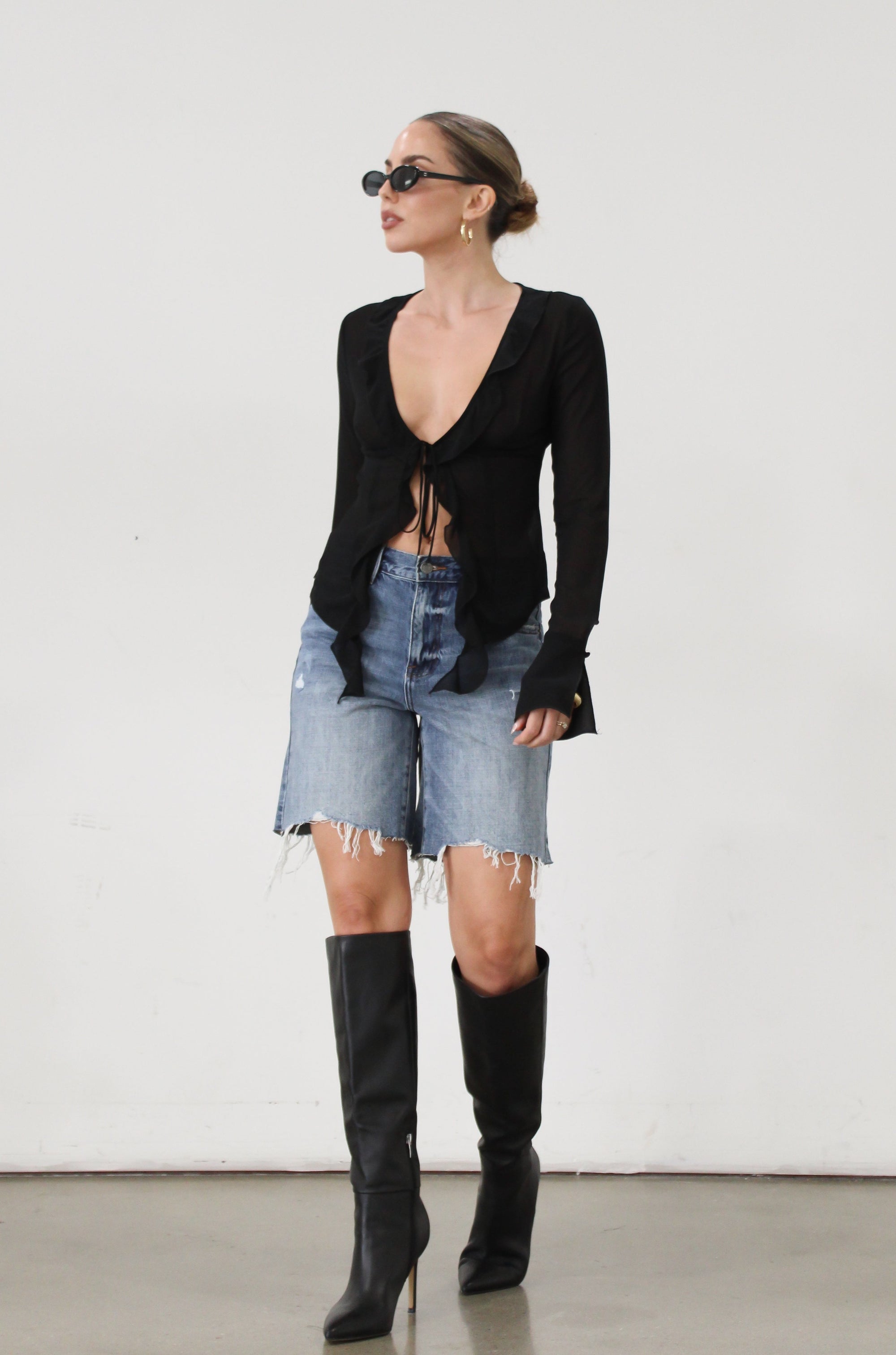 Faded and distressed denim bermuda shorts. Button and zipper fly. Five pocket construction. Frayed hem. Minimal stretch.