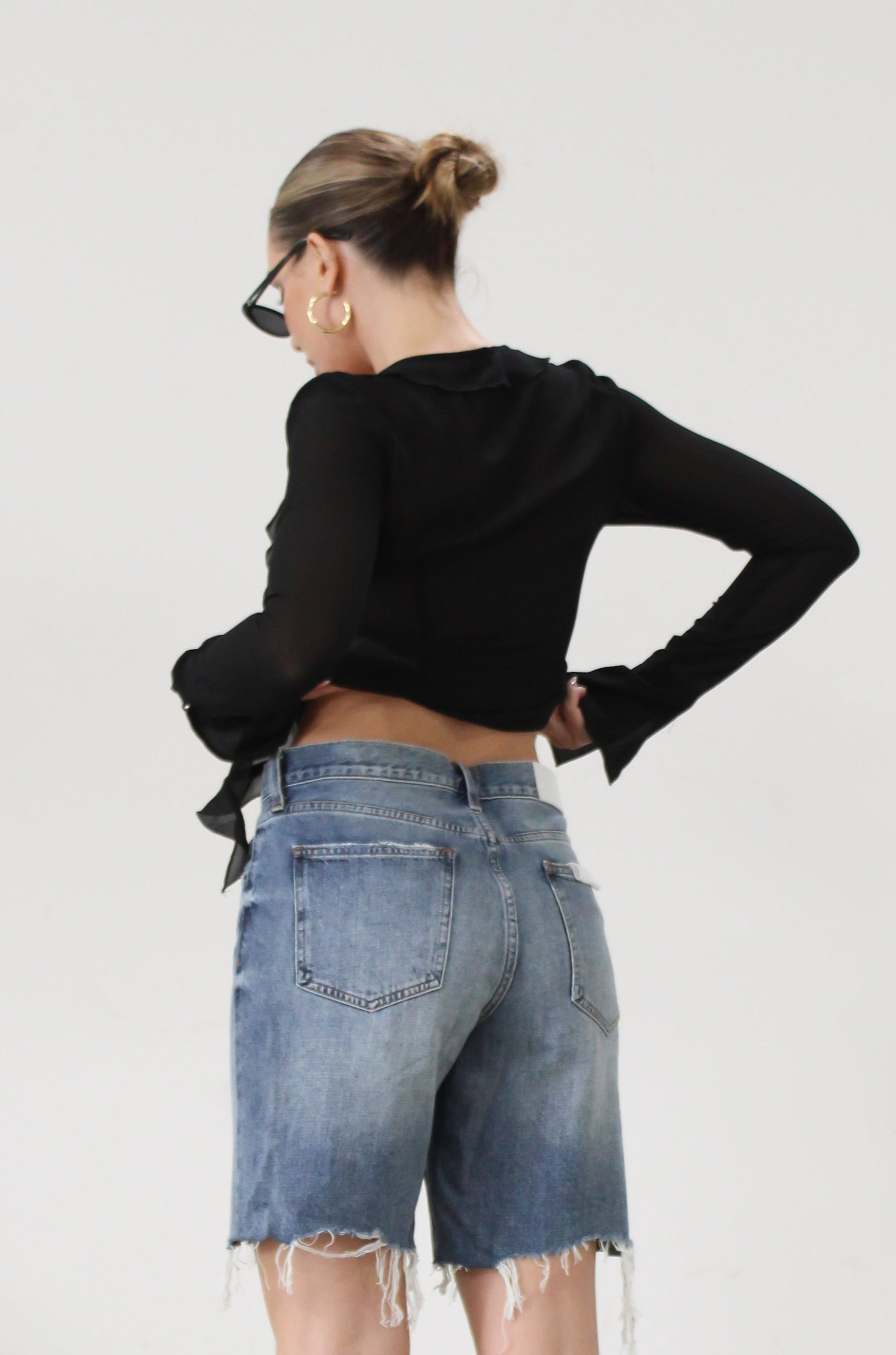 Faded and distressed denim bermuda shorts. Button and zipper fly. Five pocket construction. Frayed hem. Minimal stretch.
