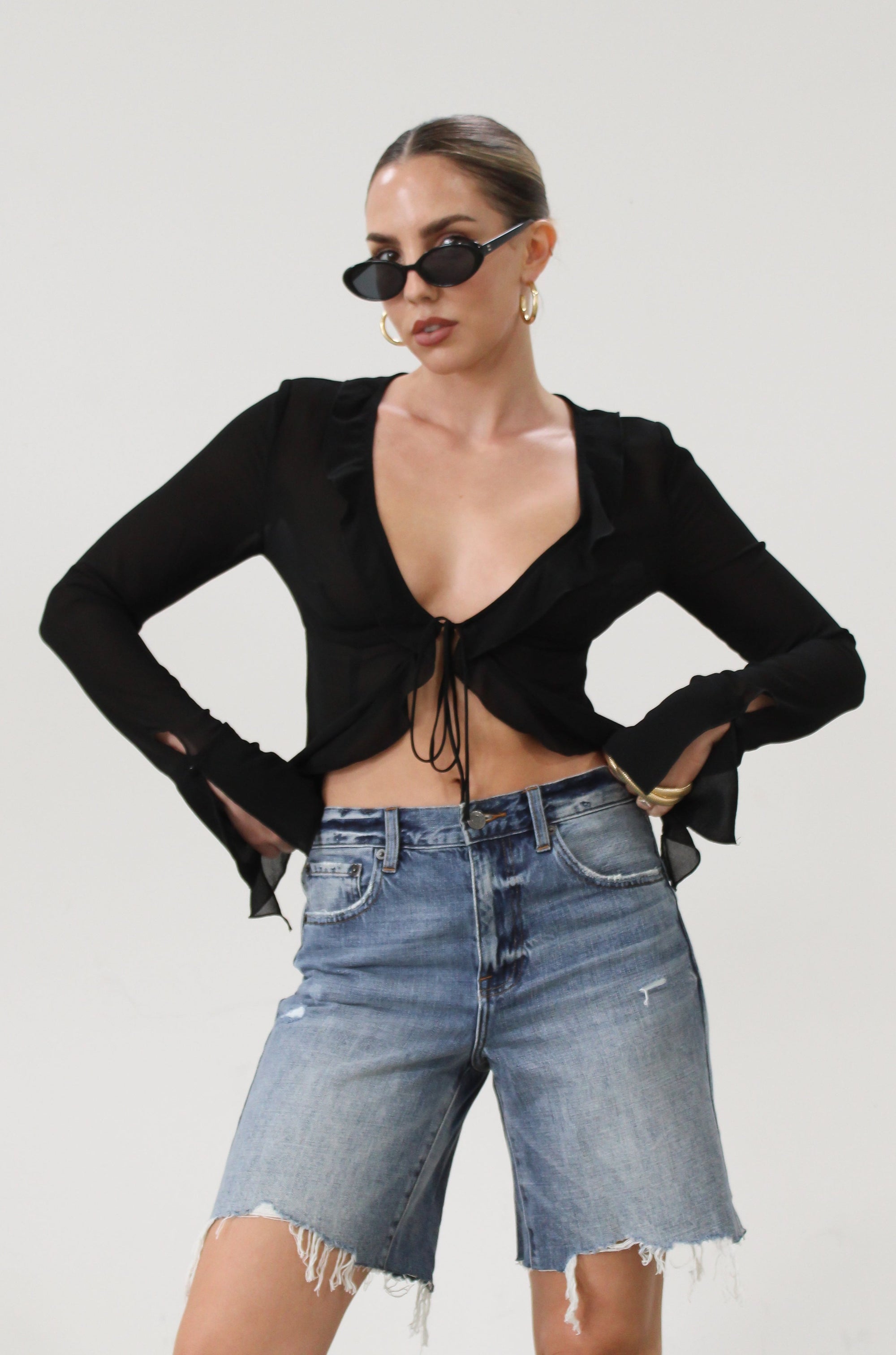 Faded and distressed denim bermuda shorts. Button and zipper fly. Five pocket construction. Frayed hem. Minimal stretch.