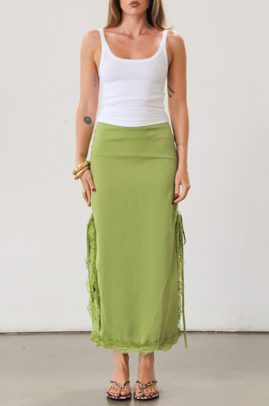 Satin maxi skirt. Side hook and eye and zipper closures. Side slits. Tie details. Lace trim. Fully lined. Green skirt.