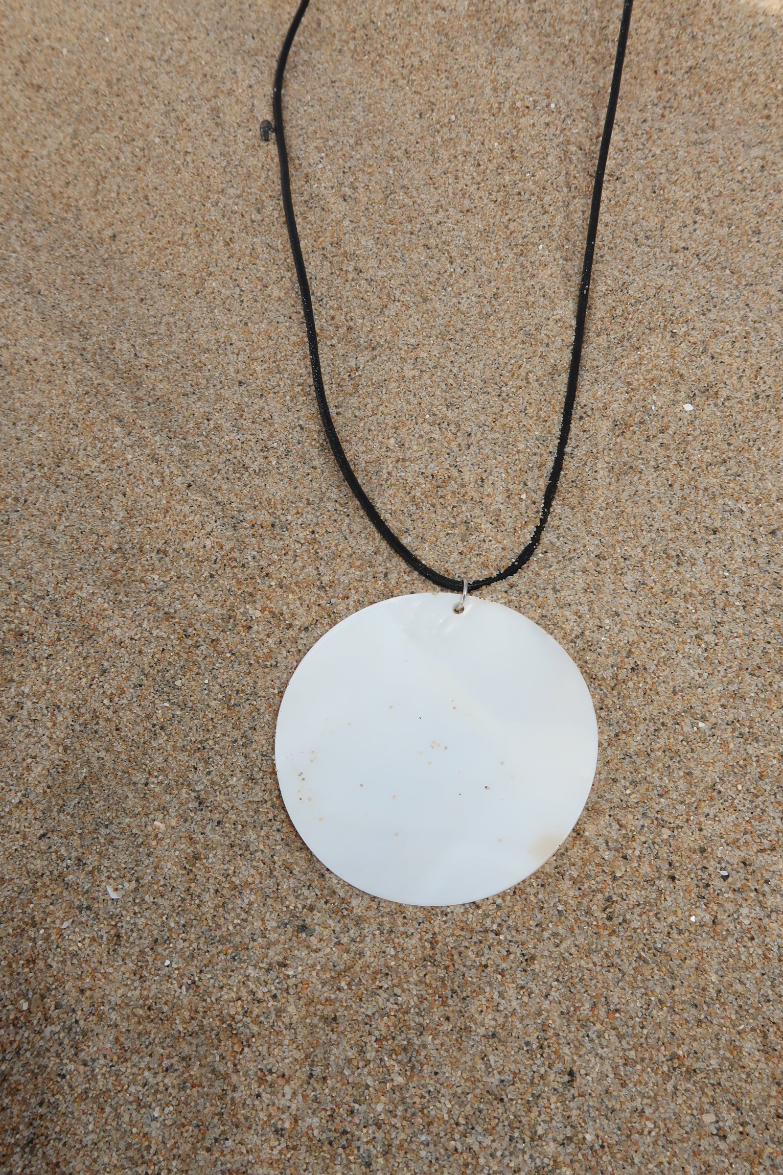 Cord necklace. Large round shell pendant. Adjustable lobster clasp closure.