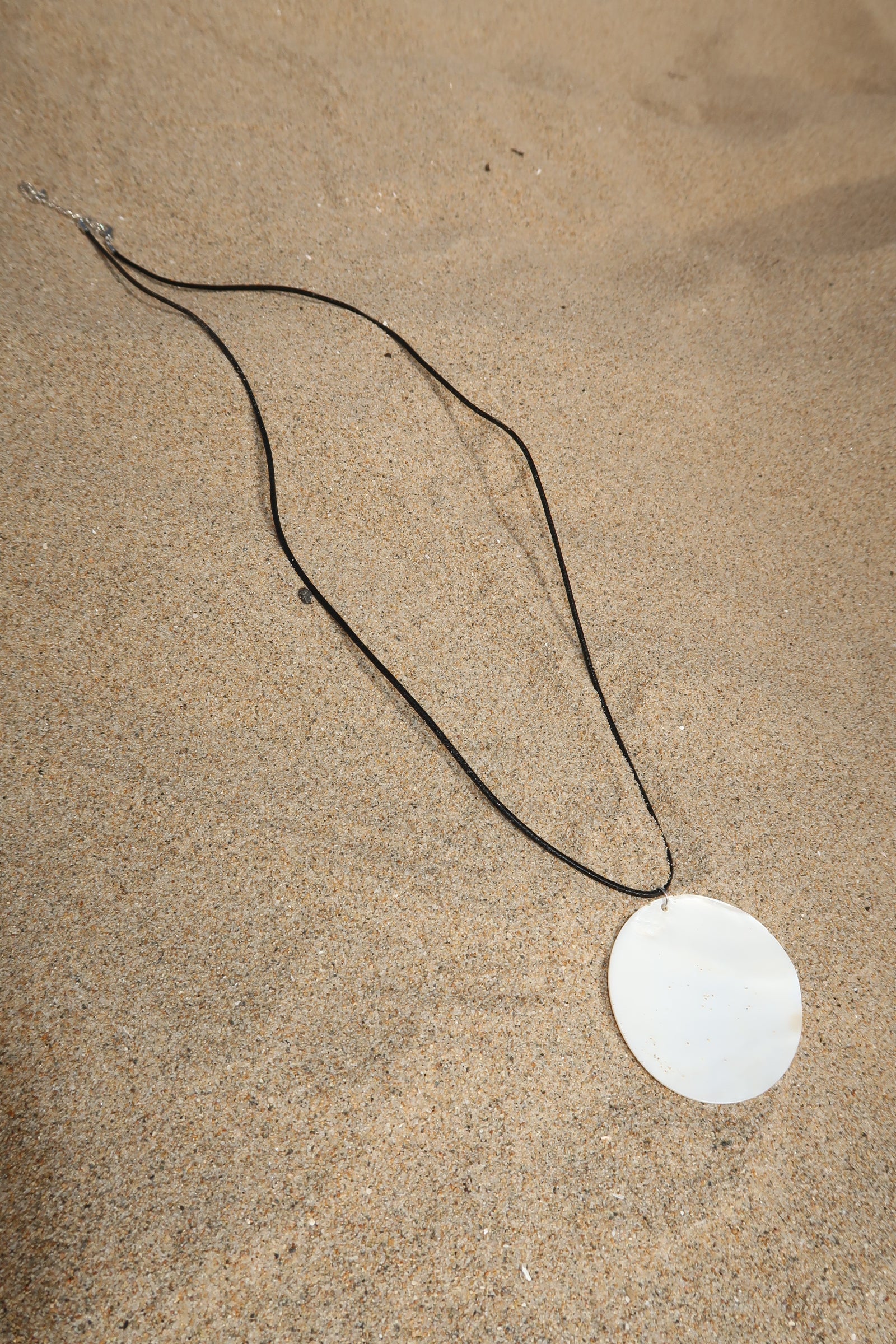 Cord necklace. Large round shell pendant. Adjustable lobster clasp closure.