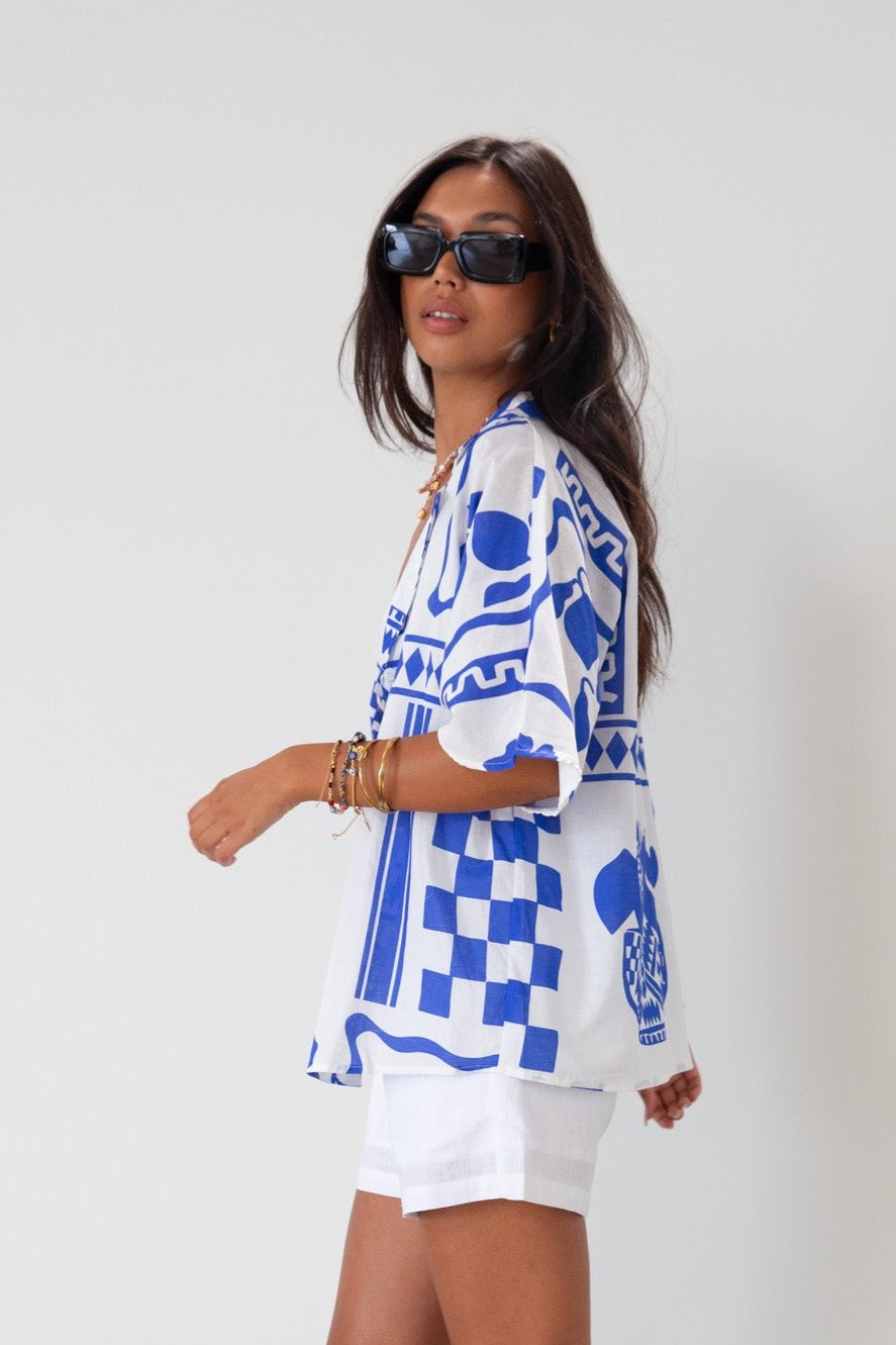 Printed woven shirt. Collar neckline. Short sleeves. Front button down closure. Unlined. cover up shirt. button up cover up. blue and white printed shirt. summer top. beach cover up. pool coverup
