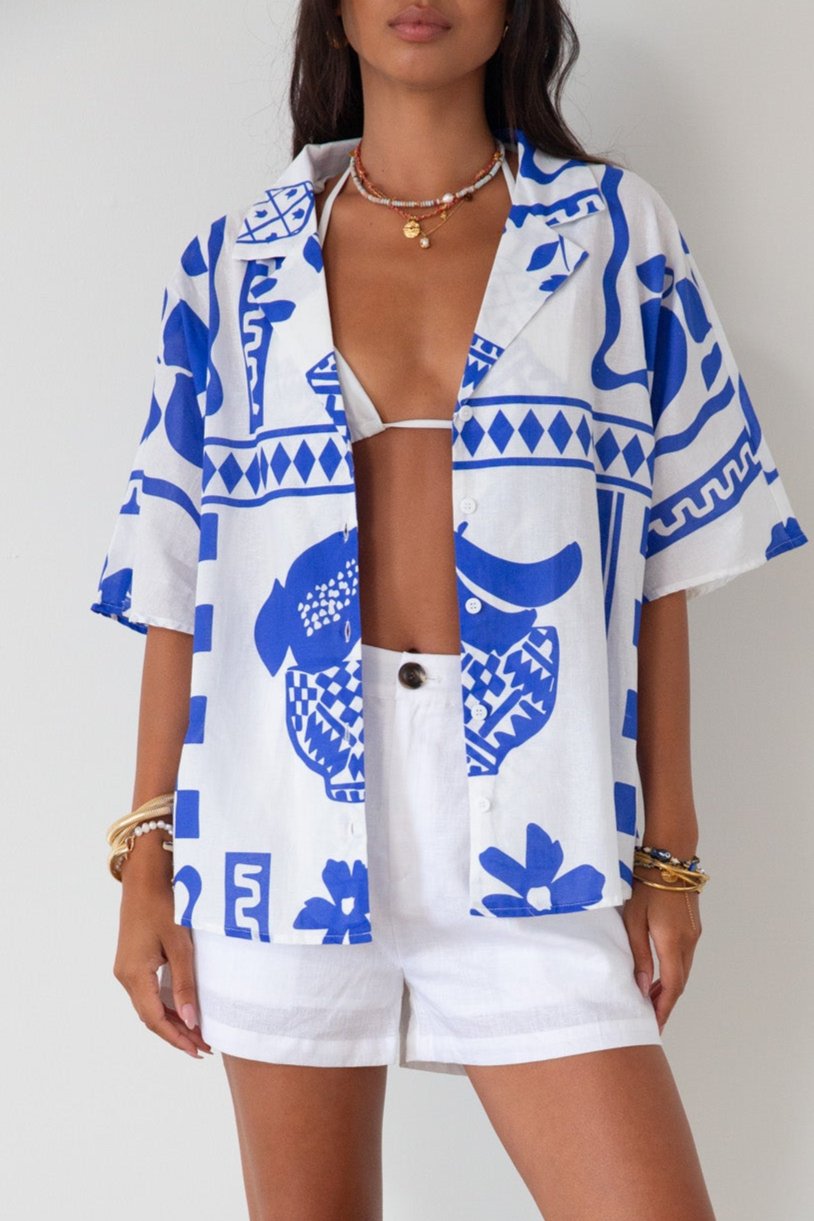 Printed woven shirt. Collar neckline. Short sleeves. Front button down closure. Unlined. cover up shirt. button up cover up. blue and white printed shirt. summer top. beach cover up. pool coverup