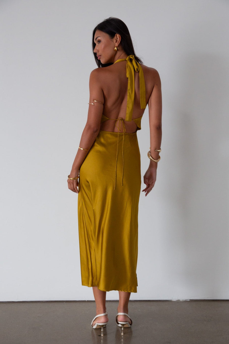 Satin maxi dress. Adjustable halter tie neckline. Side hook and eye and zipper closures. Front slit. Back tie closure. Partially lined. gold dress. gold midi dress. guest wedding dress. fall wedding. 