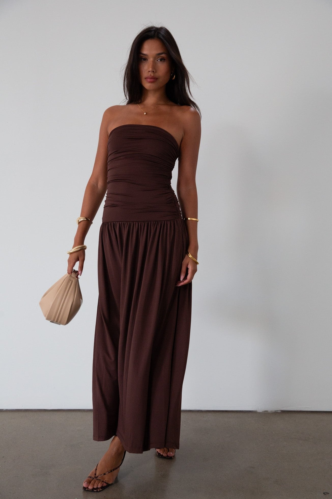 Knit maxi dress. Strapless elastic neckline. Inner rubber grip lining. Ruched slides. Partially lined. brown maxi dress. brown starpless maxi dress. summer dress. wedding guest dress