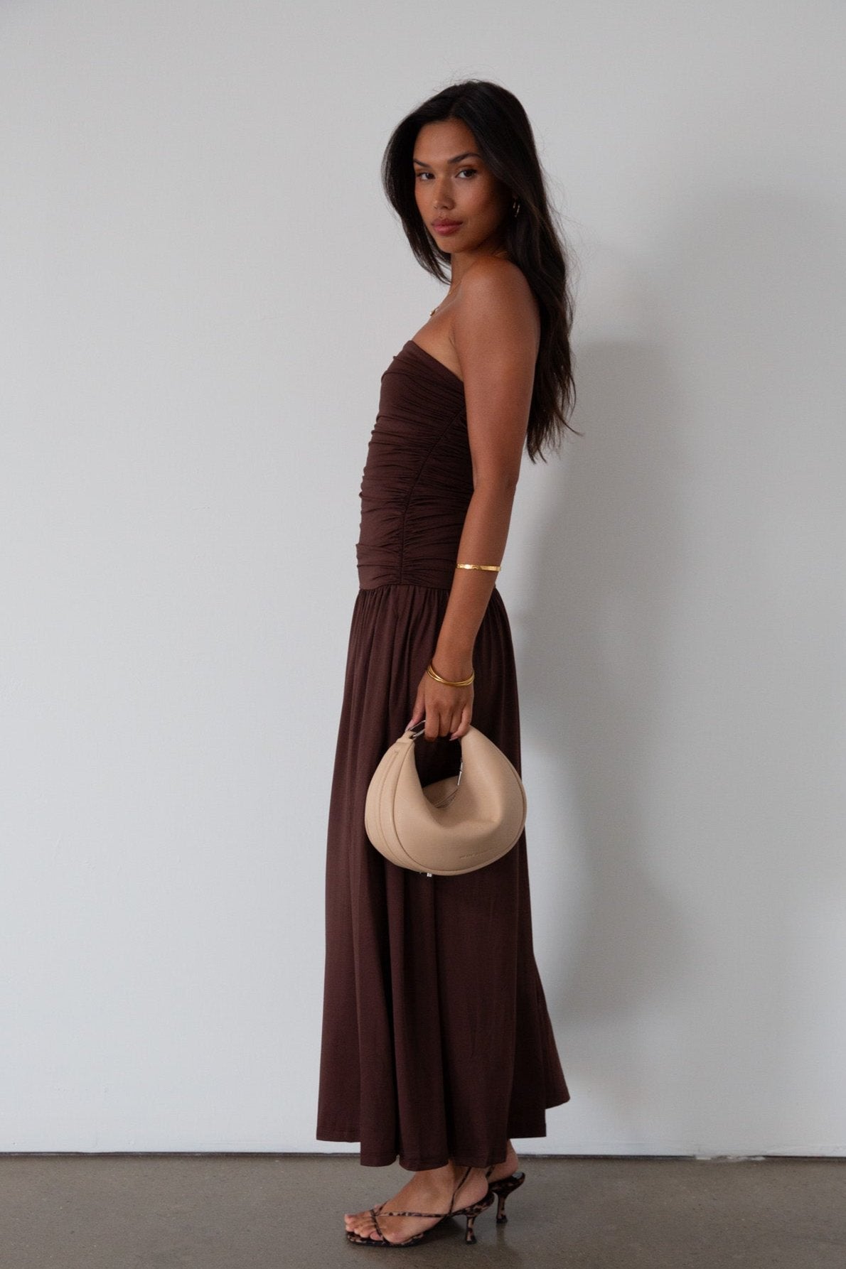 Knit maxi dress. Strapless elastic neckline. Inner rubber grip lining. Ruched slides. Partially lined. brown maxi dress. brown starpless maxi dress. summer dress. wedding guest dress