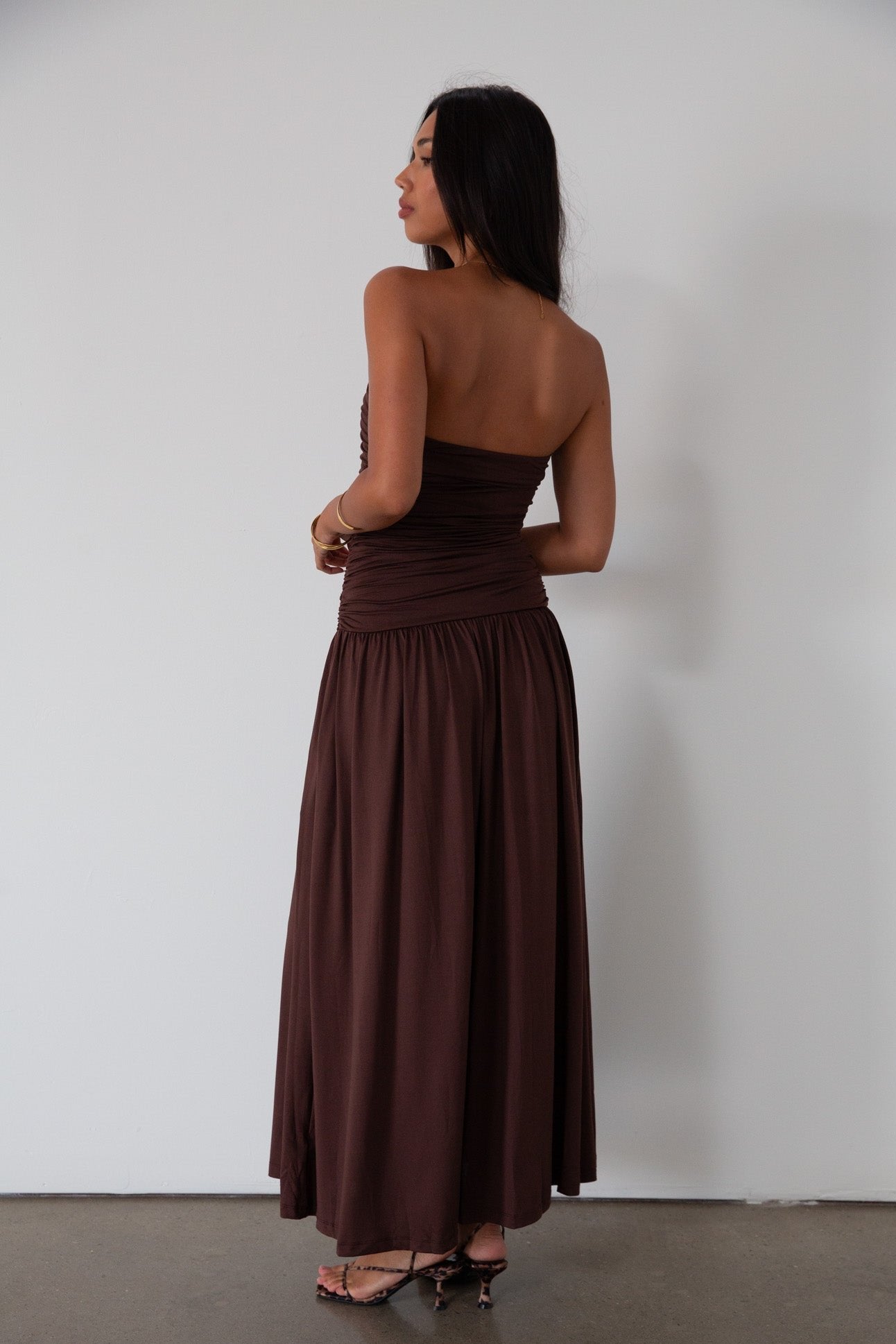 Knit maxi dress. Strapless elastic neckline. Inner rubber grip lining. Ruched slides. Partially lined. brown maxi dress. brown starpless maxi dress. summer dress. wedding guest dress