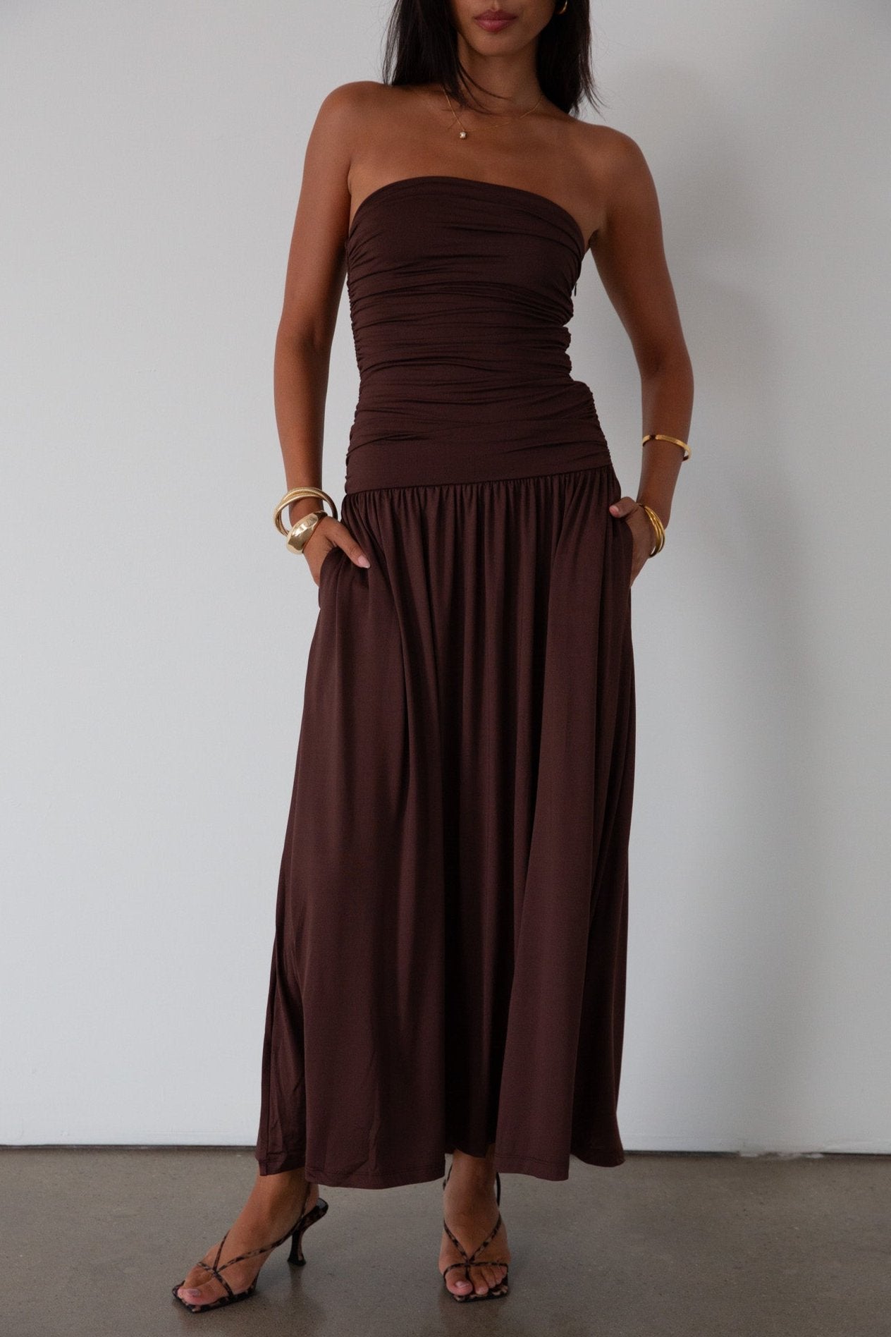 Knit maxi dress. Strapless elastic neckline. Inner rubber grip lining. Ruched slides. Partially lined. brown maxi dress. brown starpless maxi dress. summer dress. wedding guest dress