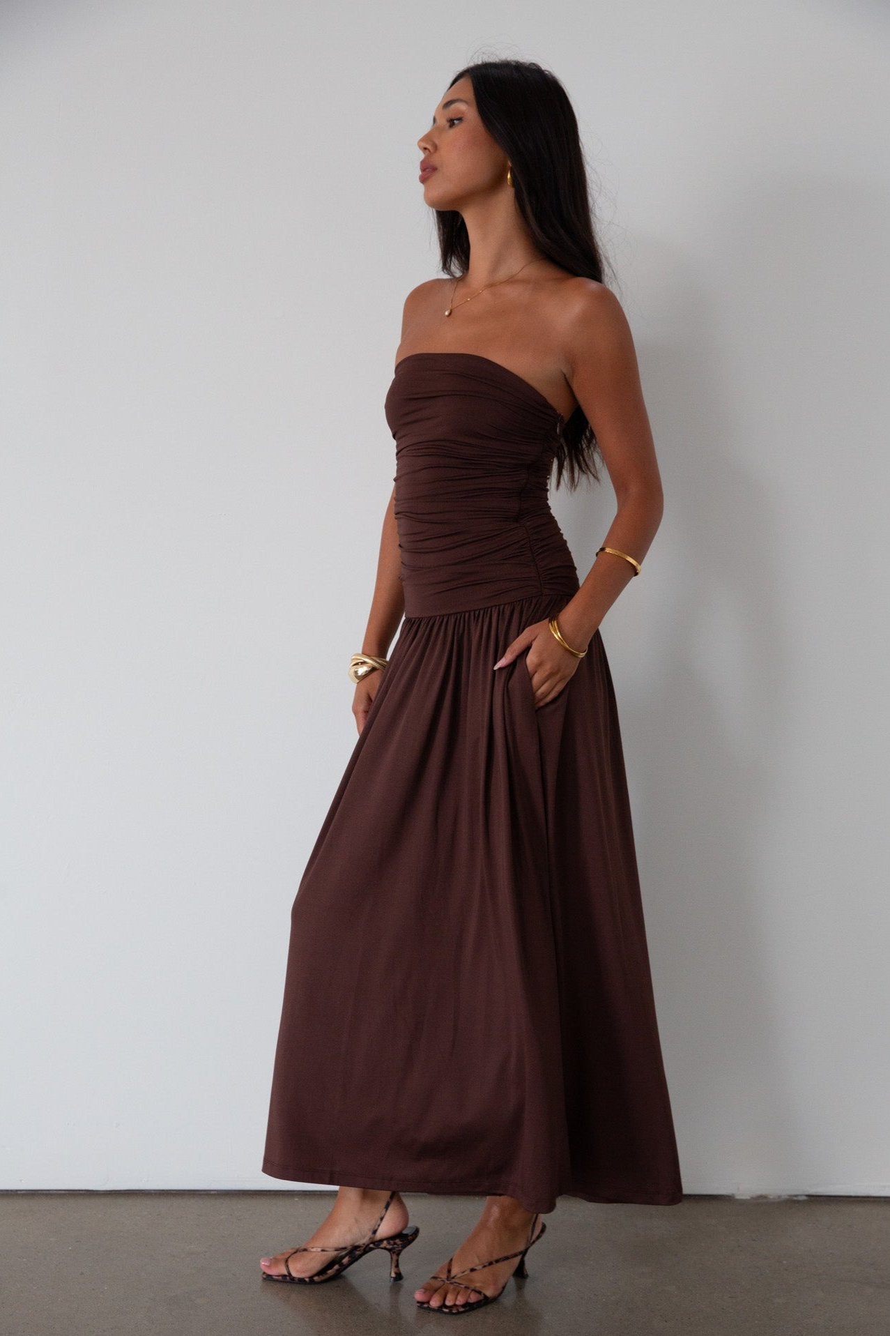 Knit maxi dress. Strapless elastic neckline. Inner rubber grip lining. Ruched slides. Partially lined. brown maxi dress. brown starpless maxi dress. summer dress. wedding guest dress