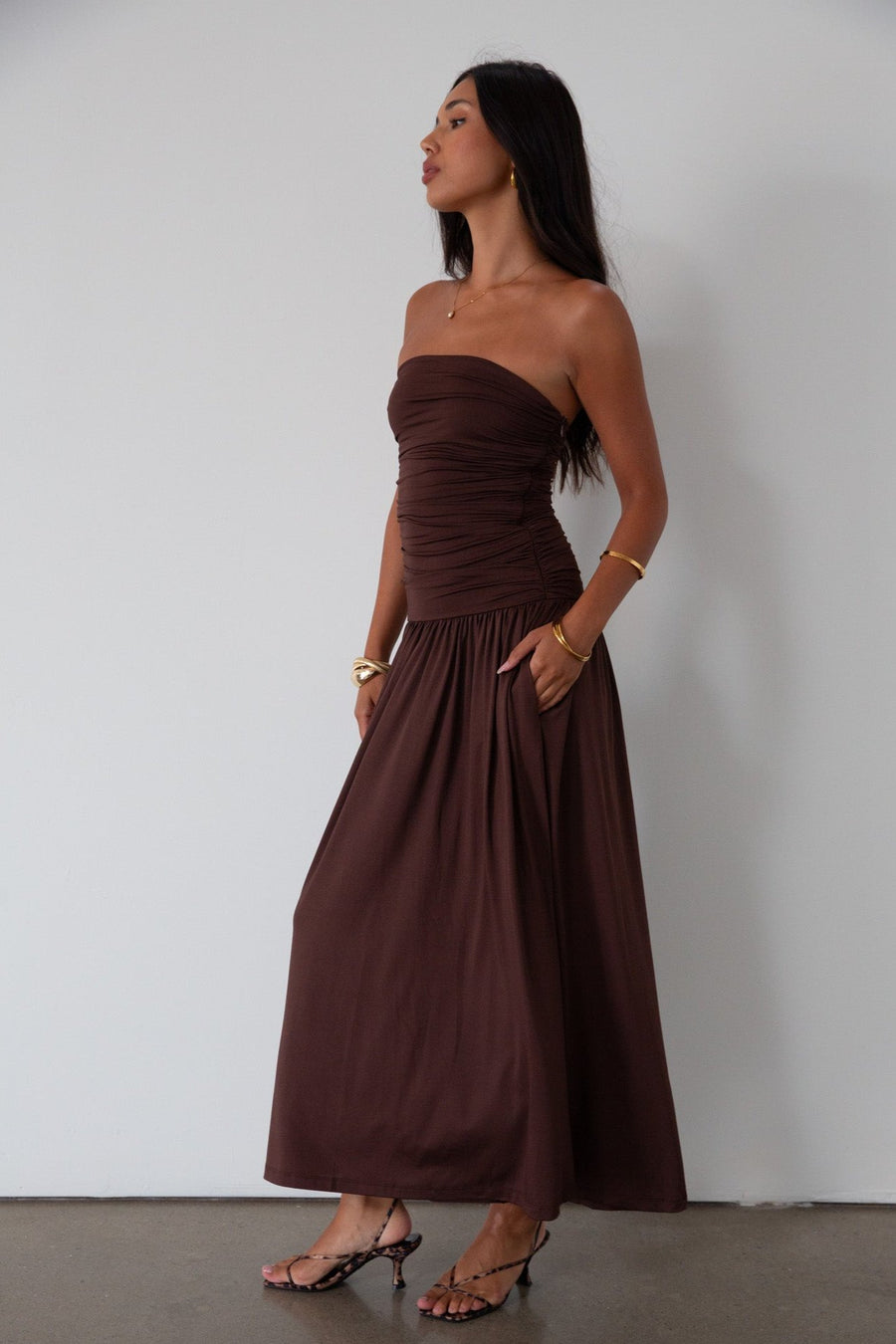 Knit maxi dress. Strapless elastic neckline. Inner rubber grip lining. Ruched slides. Partially lined. brown maxi dress. brown starpless maxi dress. summer dress. wedding guest dress