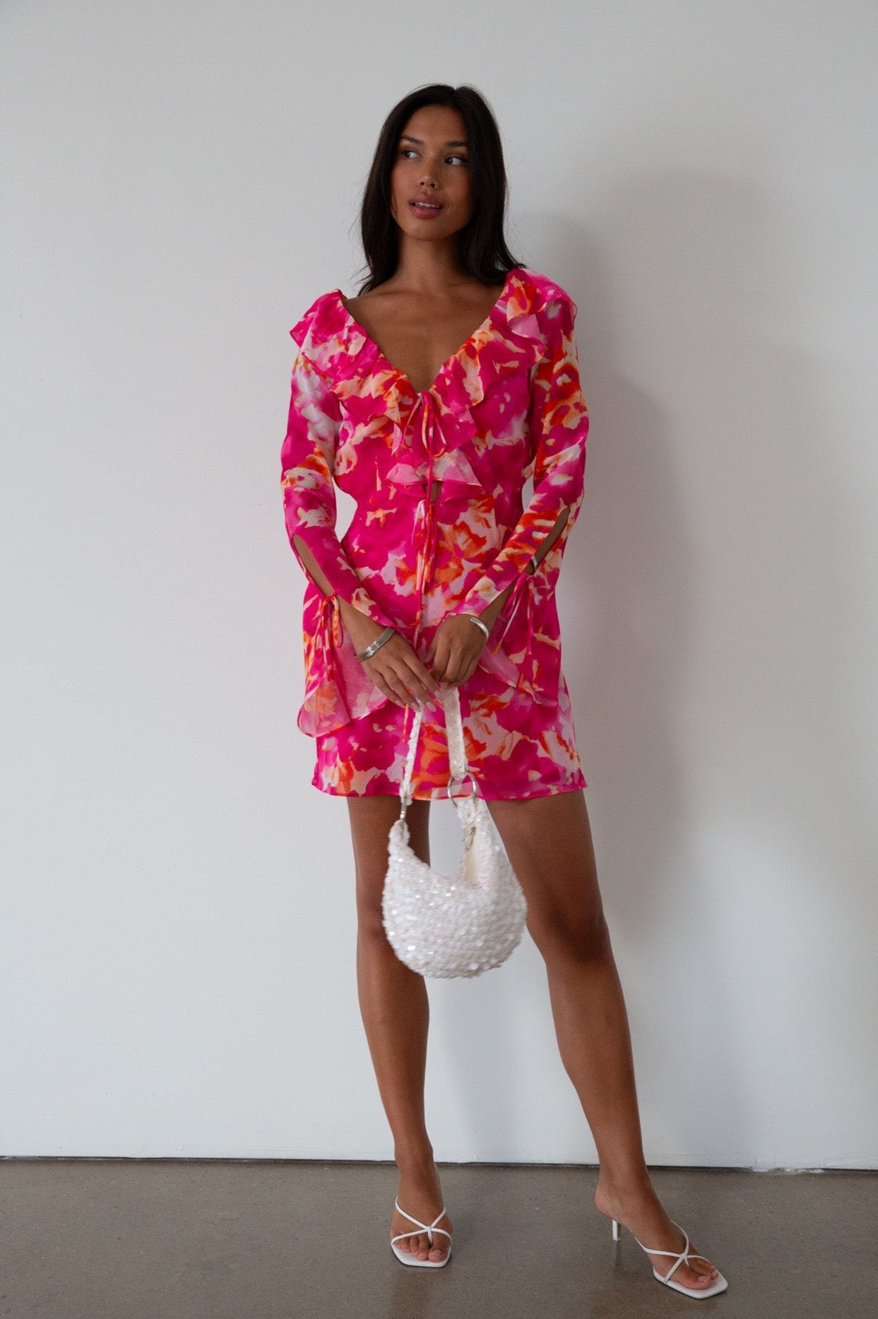 Printed chiffon dress. Long sleeves with tie closure. Front and back tie closures. Ruffle deep v-neckline. Side zipper closure. Fully lined. floral mini dress. pink floral mini dress