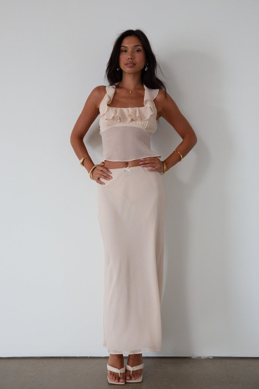 Chiffon crop top. Halter neckline with back button closures. Ruffle trimmed deep v-neckline. Side hook and eye and zipper closures. Partially lined. ruffle top. ruffle tank top. nude top. coquette top