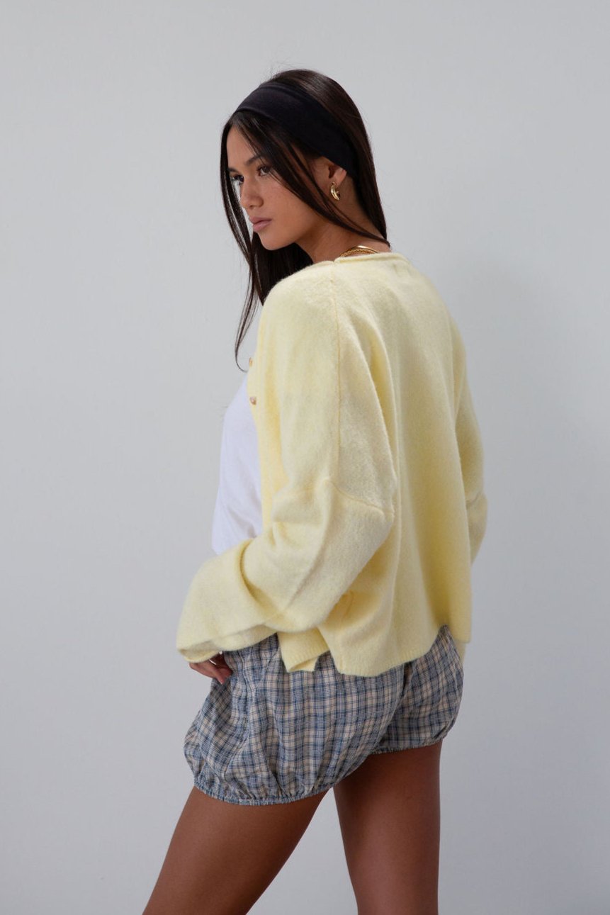 Fuzzy butter yellow knit cardigan. Crewneck. Front button down closures. Long sleeves. Unlined. fall transition outfit.