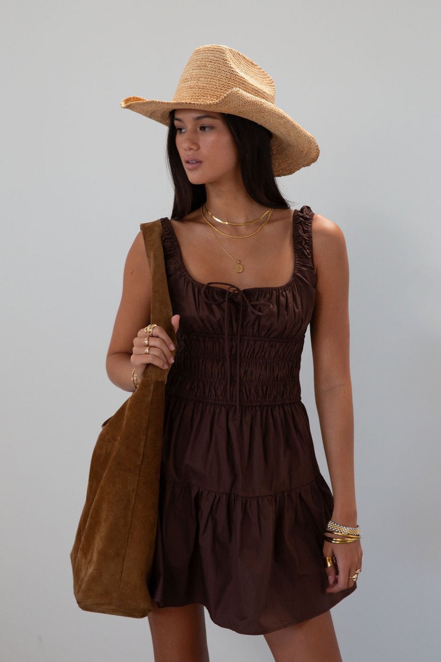 Smocked woven dress. Elastic straps. Front tie closure. Elastic waist. Side pockets. Fully lined. brown mini dress. fall transition dress