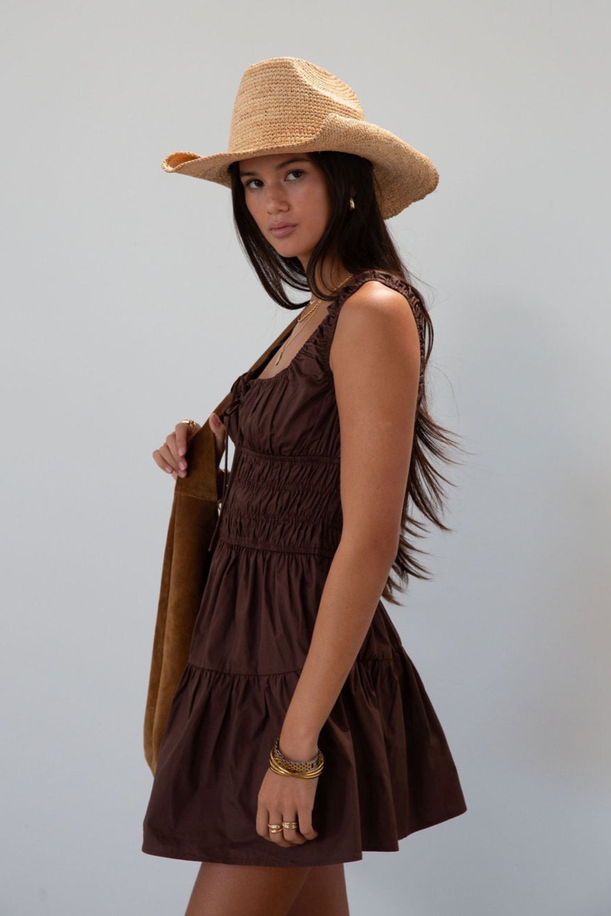 Smocked woven dress. Elastic straps. Front tie closure. Elastic waist. Side pockets. Fully lined. brown mini dress. fall transition dress