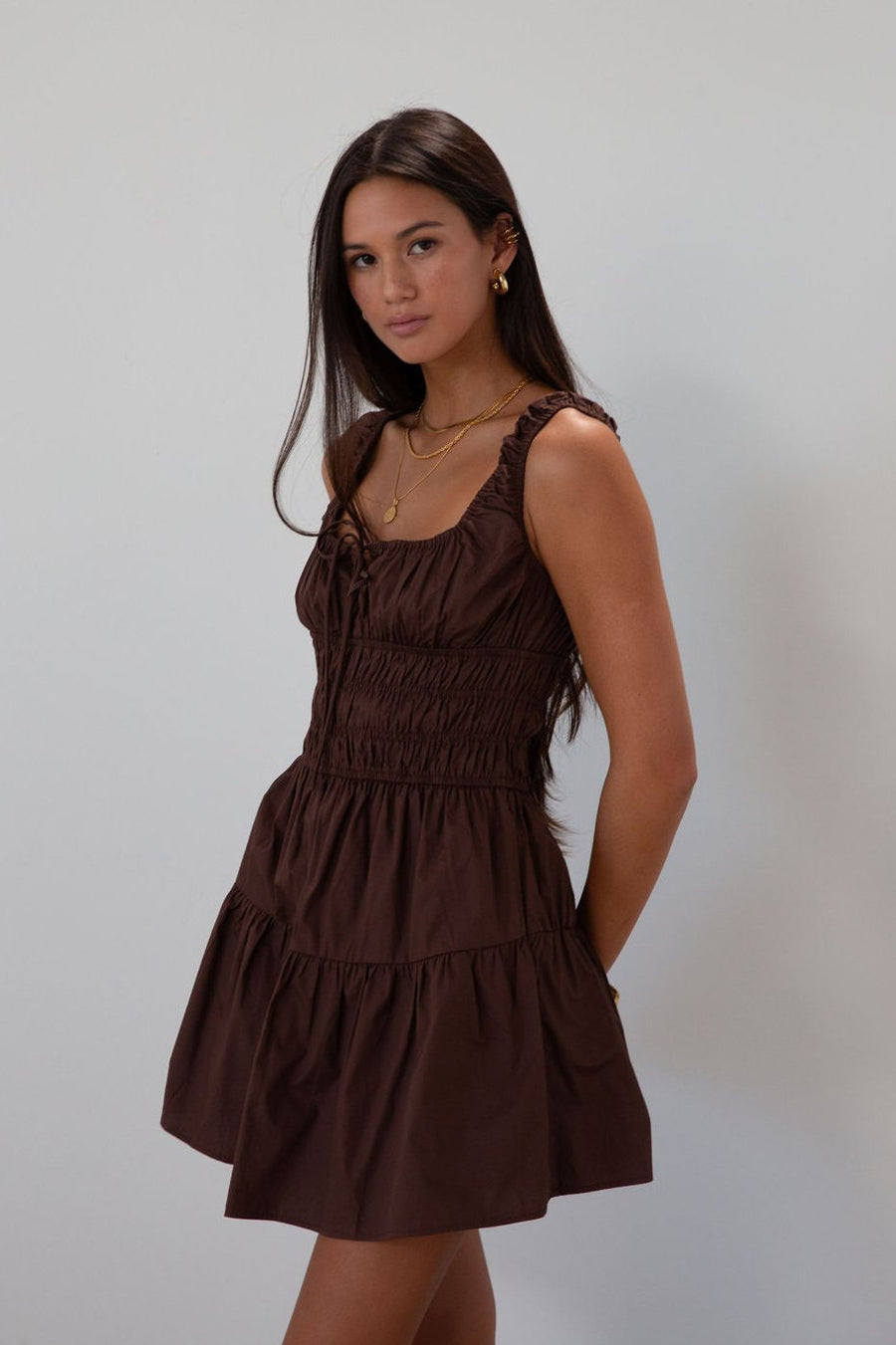 Smocked woven dress. Elastic straps. Front tie closure. Elastic waist. Side pockets. Fully lined. brown mini dress. fall transition dress