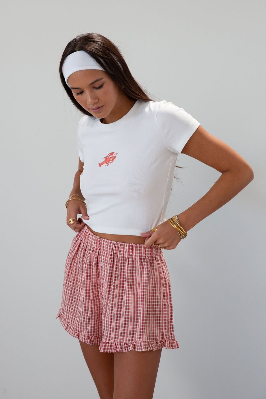 Checkered woven shorts. Elastic waist. Faux button fly. Ruffle trim hem. Unlined. red checkered shorts