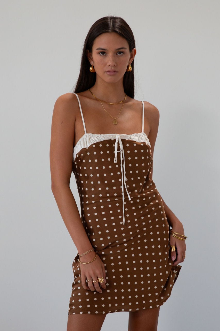 Polka dot printed satin dress. Adjustable straps. Front tie closure. Back hook and eye and zipper closures. Fully lined. brown mini dress. brown polka dot dress. fall outfit