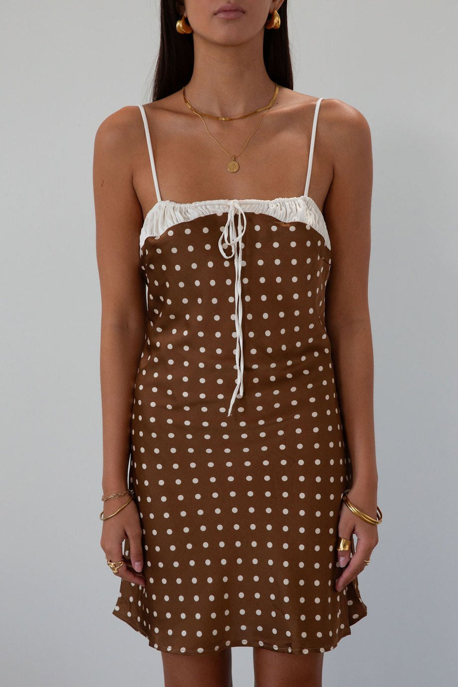 Polka dot printed satin dress. Adjustable straps. Front tie closure. Back hook and eye and zipper closures. Fully lined. brown mini dress. brown polka dot dress. fall outfit