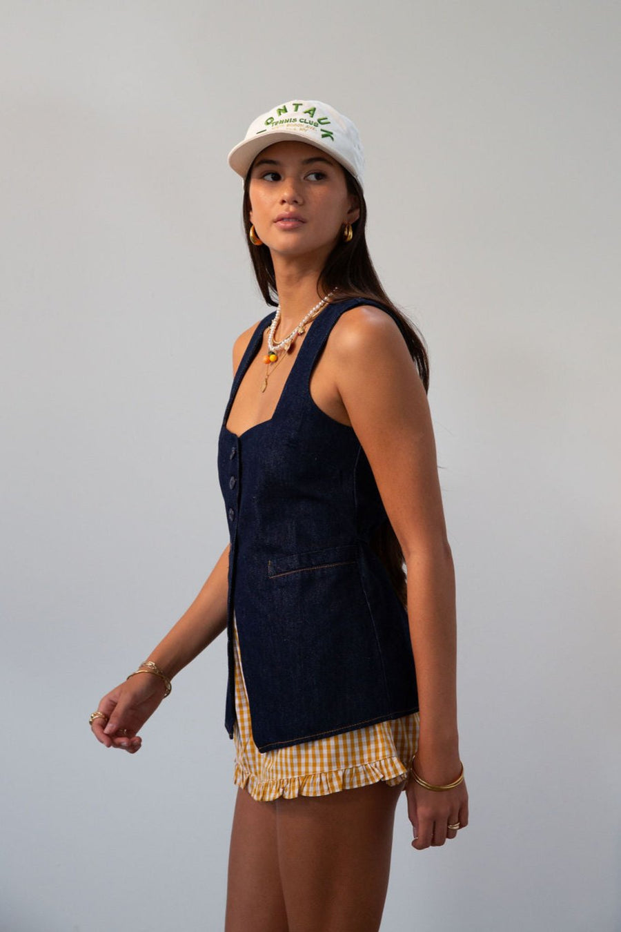 Denim sleeveless top. Fixed straps. Front button down closures. Faux front pockets. Adjustable back tie closure. Unlined. denim vest