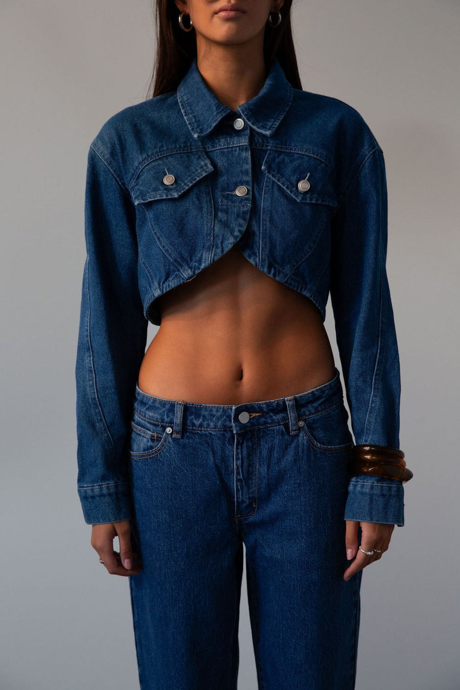 Cropped denim jacket. Collar neckline. Long sleeves with button closures. Front button closures. Unlined.