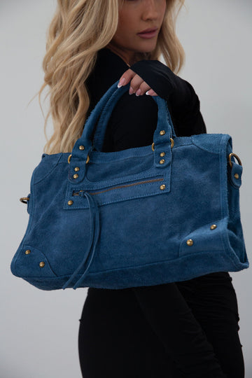 blue Suede bag. Adjustable/detachable strap. Fixed top handles. Top zipper closure. Front zipper pocket. Fully lined. Inner pockets and zipper pocket.