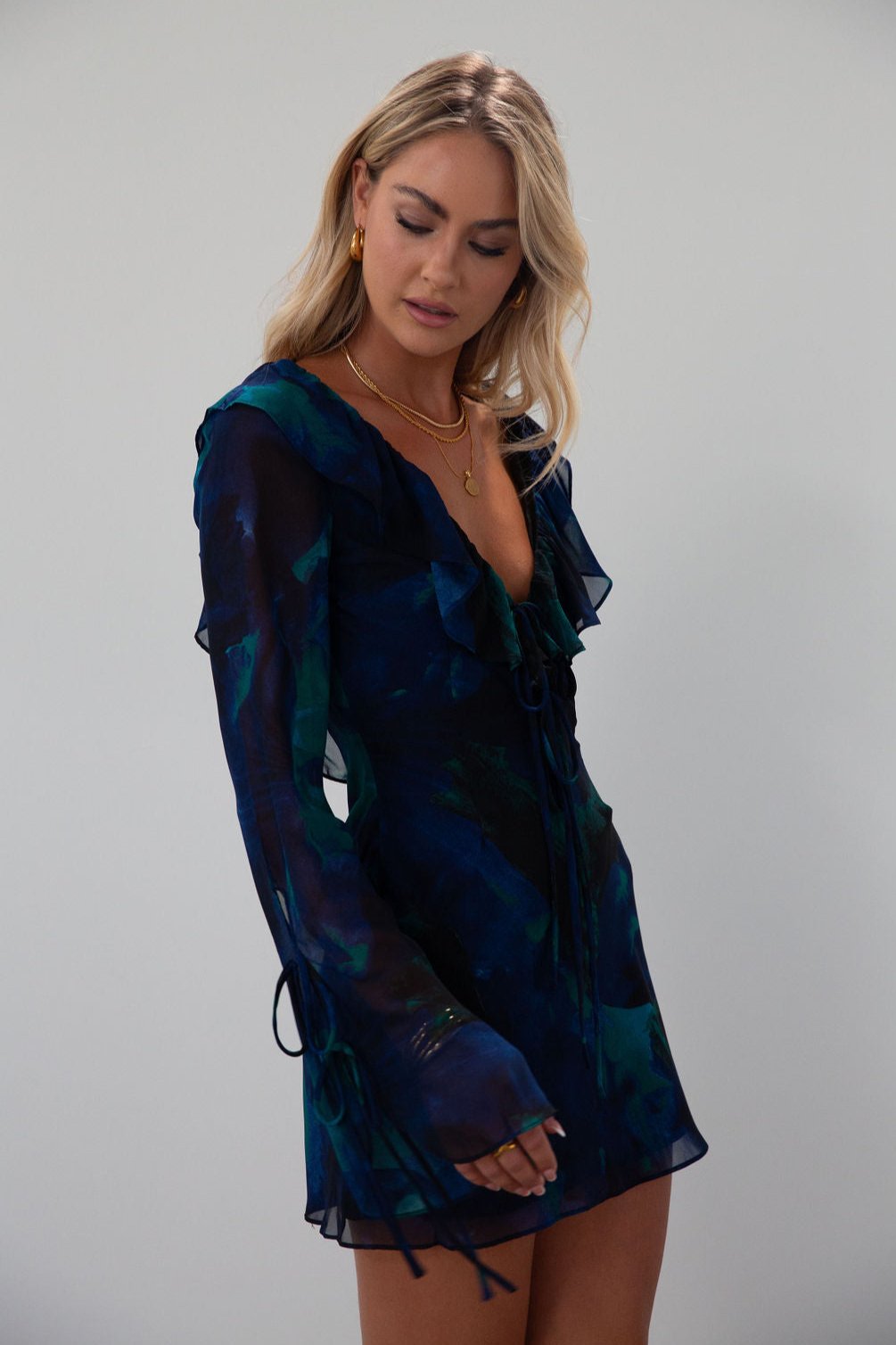 Printed chiffon dress. Long sleeves with tie closures. Ruffle trim. Front and back tie closures. Side zipper closure. Fully lined. mini dress. blue and green mini dress. fall outfit