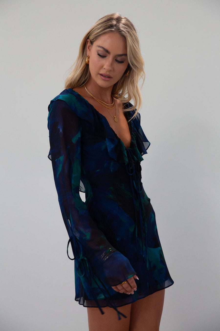 Printed chiffon dress. Long sleeves with tie closures. Ruffle trim. Front and back tie closures. Side zipper closure. Fully lined. mini dress. blue and green mini dress. fall outfit