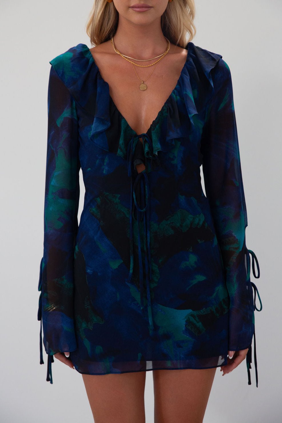 Printed chiffon dress. Long sleeves with tie closures. Ruffle trim. Front and back tie closures. Side zipper closure. Fully lined. mini dress. blue and green mini dress. fall outfit