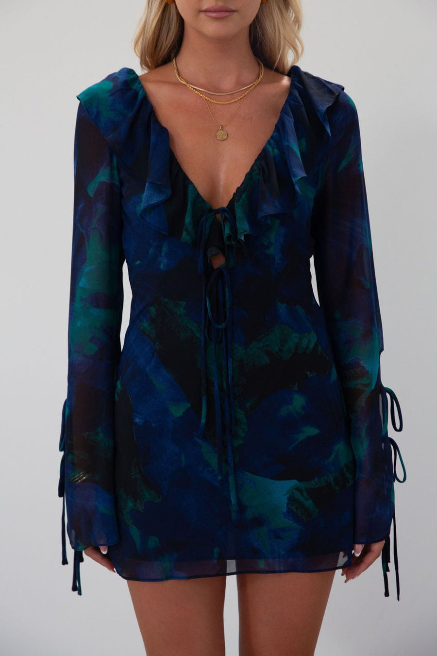 Printed chiffon dress. Long sleeves with tie closures. Ruffle trim. Front and back tie closures. Side zipper closure. Fully lined. mini dress. blue and green mini dress. fall outfit