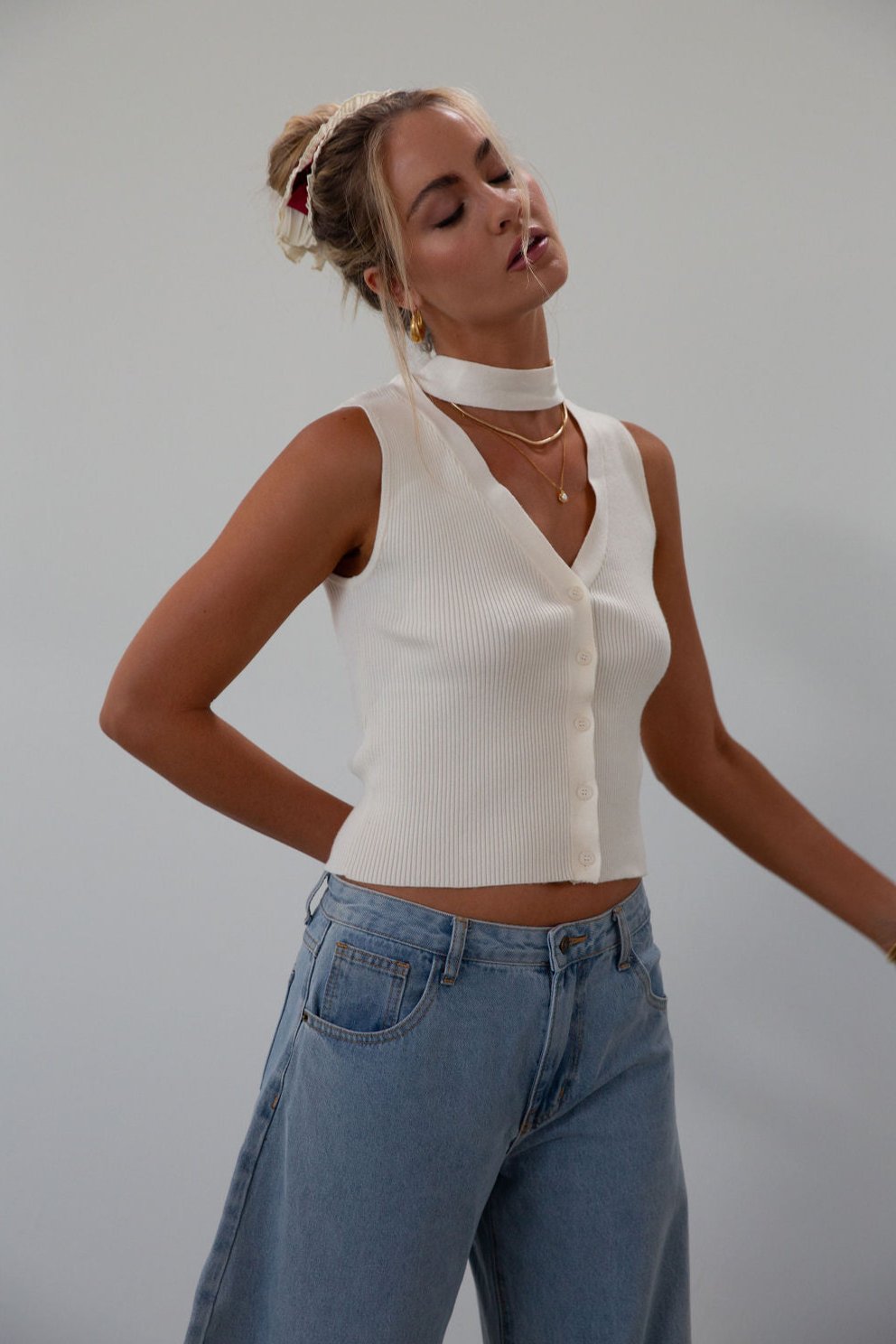 Ribbed knit sleeveless top. V-neckline. Front button down closure. Unlined. Neck tie. white top. white knit vest. fall outfit. fall top. fall transition top.