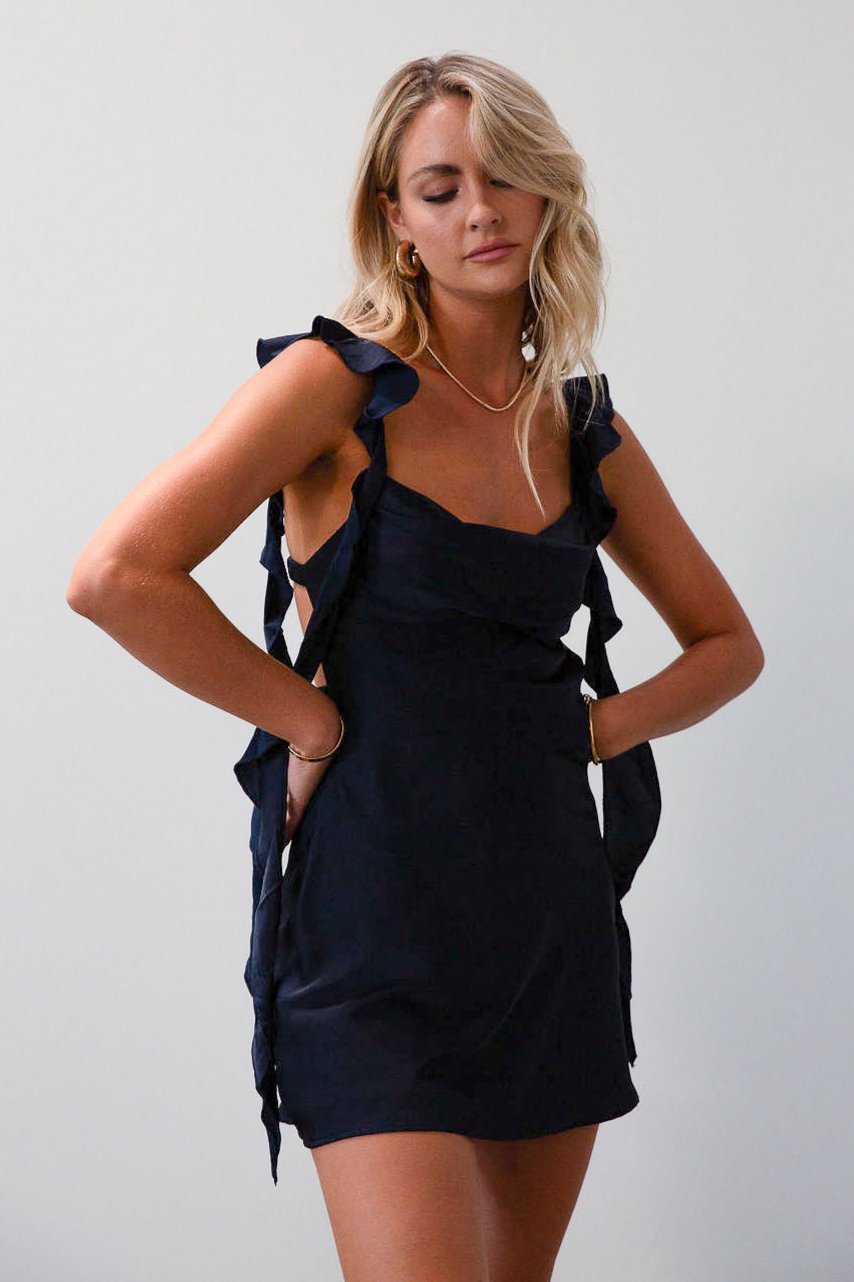 Satin dress. Adjustable straps with ruffle trim. Side hook and eye and zipper closures. Elastic back strap with clasp closure. Fully lined. navy blue mini dress. holiday dress. mini holiday dress