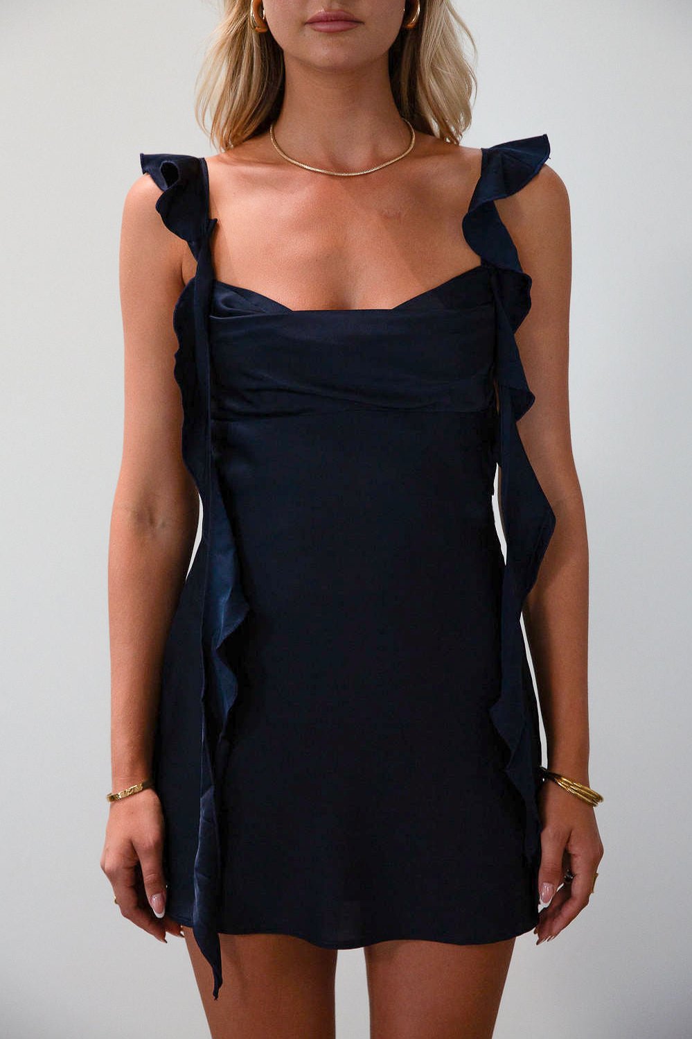 Satin dress. Adjustable straps with ruffle trim. Side hook and eye and zipper closures. Elastic back strap with clasp closure. Fully lined. navy blue mini dress. holiday dress. mini holiday dress