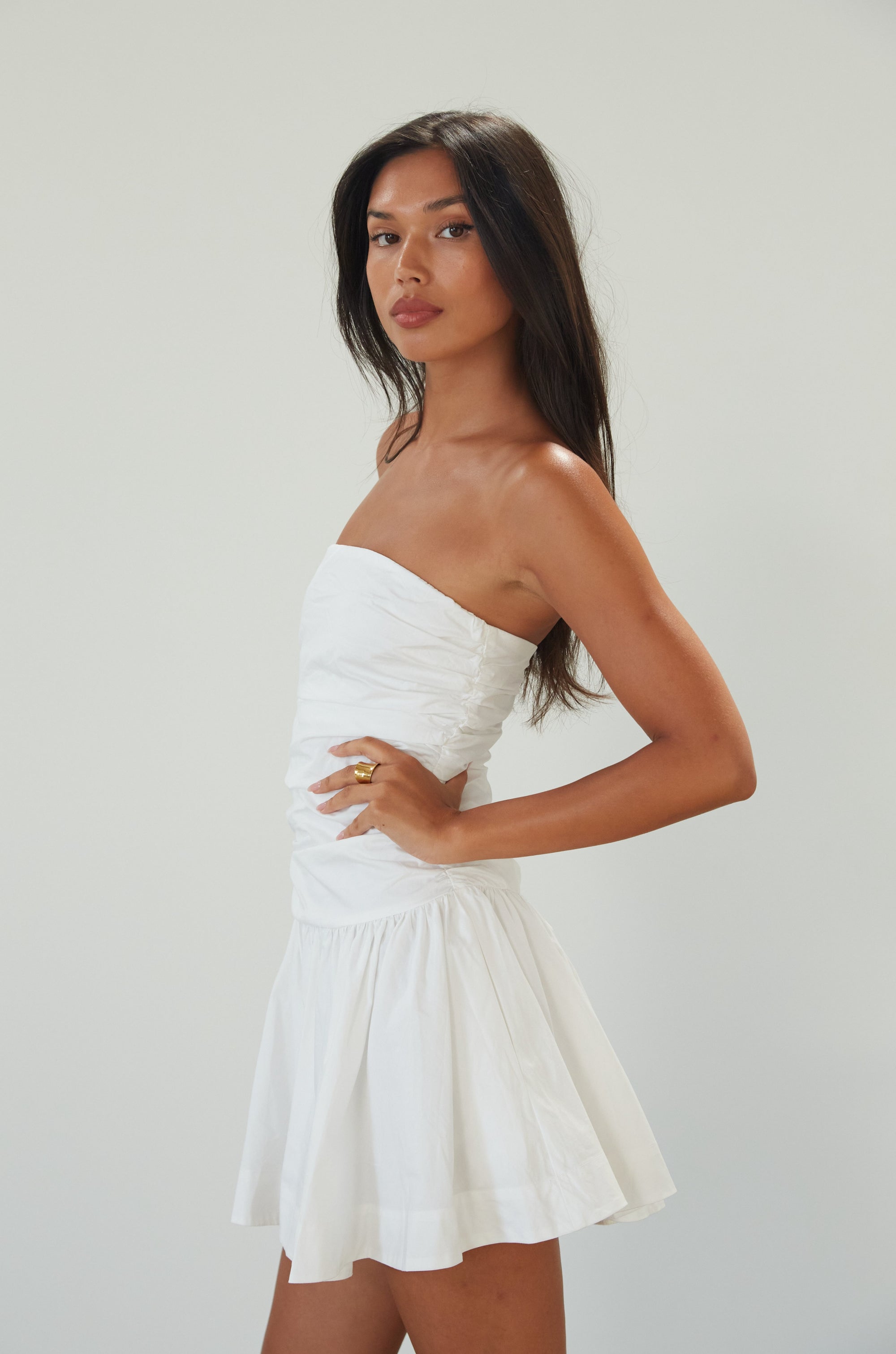Woven mini dress. Strapless neckline. Inner rubber grip lining. Ruched bodice. Back hook and eye and zipper closure. Fully lined. white mini dress. white strapless mini dress. bridal shower dress. bridal dress. engagement dress. bride outfit. summer dress. fancy dinner dress