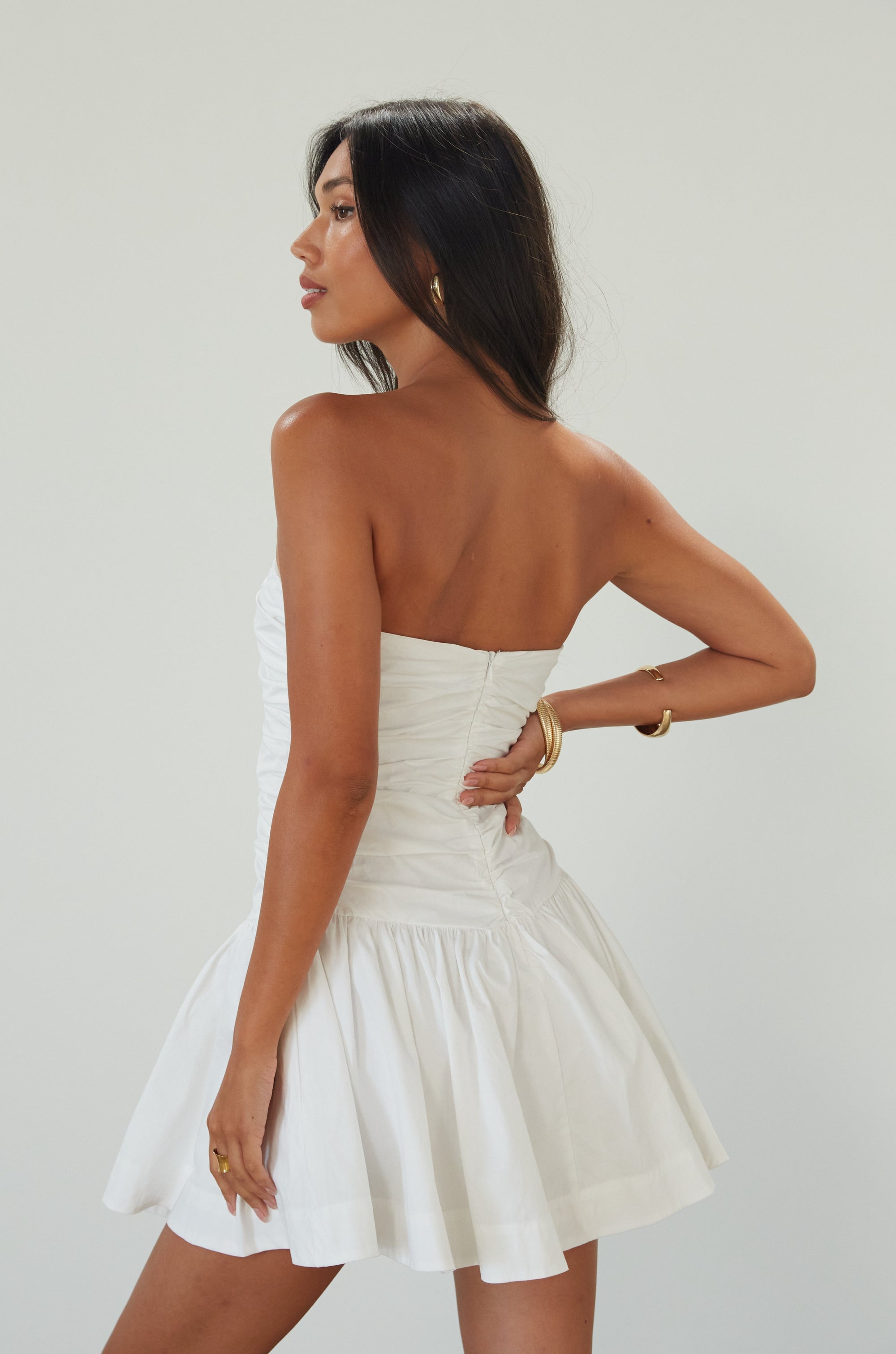 Woven mini dress. Strapless neckline. Inner rubber grip lining. Ruched bodice. Back hook and eye and zipper closure. Fully lined. white mini dress. white strapless mini dress. bridal shower dress. bridal dress. engagement dress. bride outfit. summer dress. fancy dinner dress