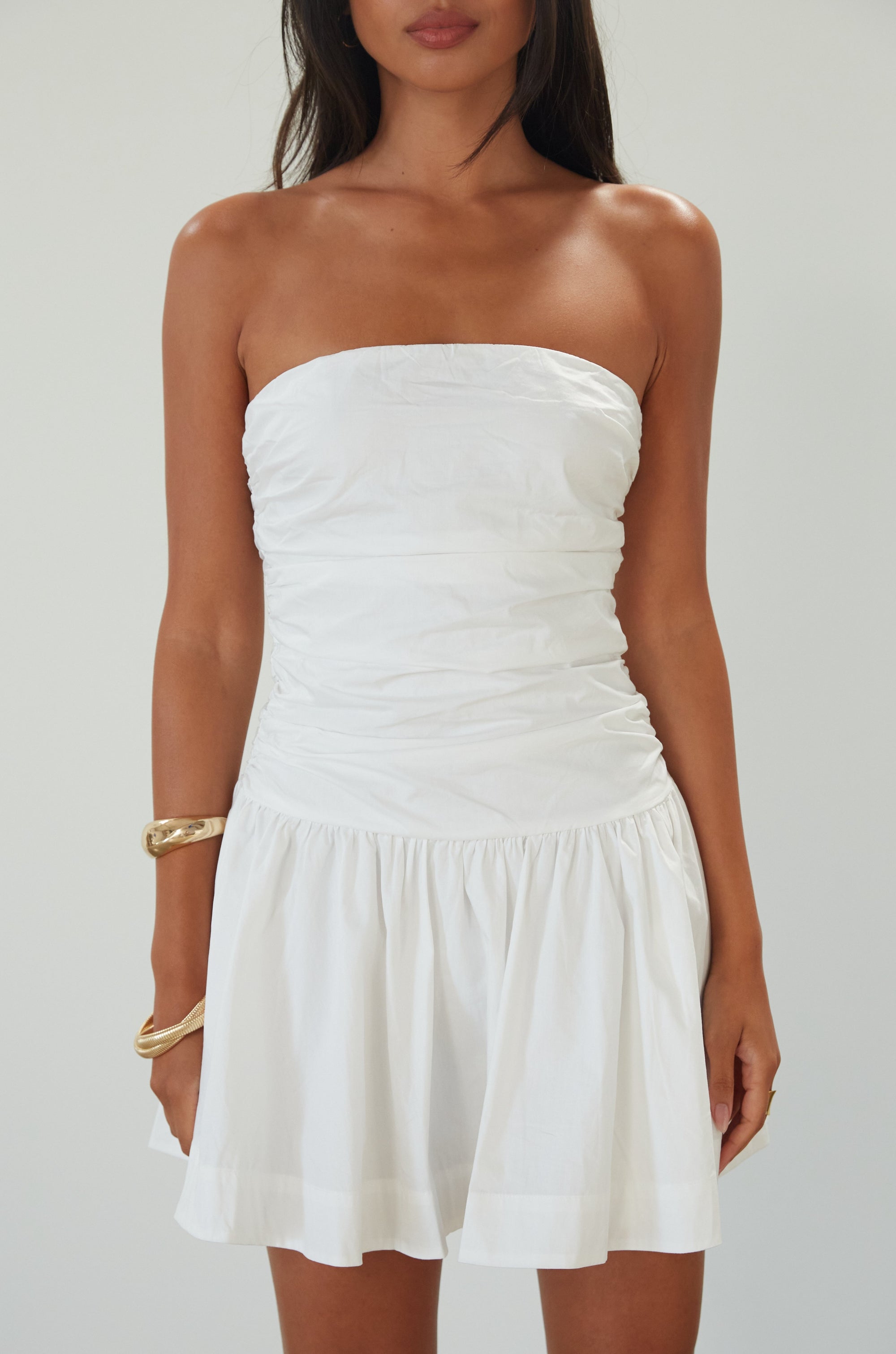 Woven mini dress. Strapless neckline. Inner rubber grip lining. Ruched bodice. Back hook and eye and zipper closure. Fully lined. white mini dress. white strapless mini dress. bridal shower dress. bridal dress. engagement dress. bride outfit. summer dress. fancy dinner dress