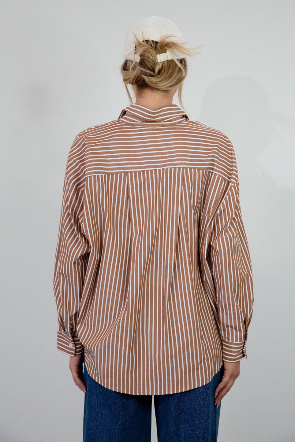 brown and white Striped woven shirt. Collar neckline. Long sleeves with button closures. Front button down closures. Unlined. oversized button down top