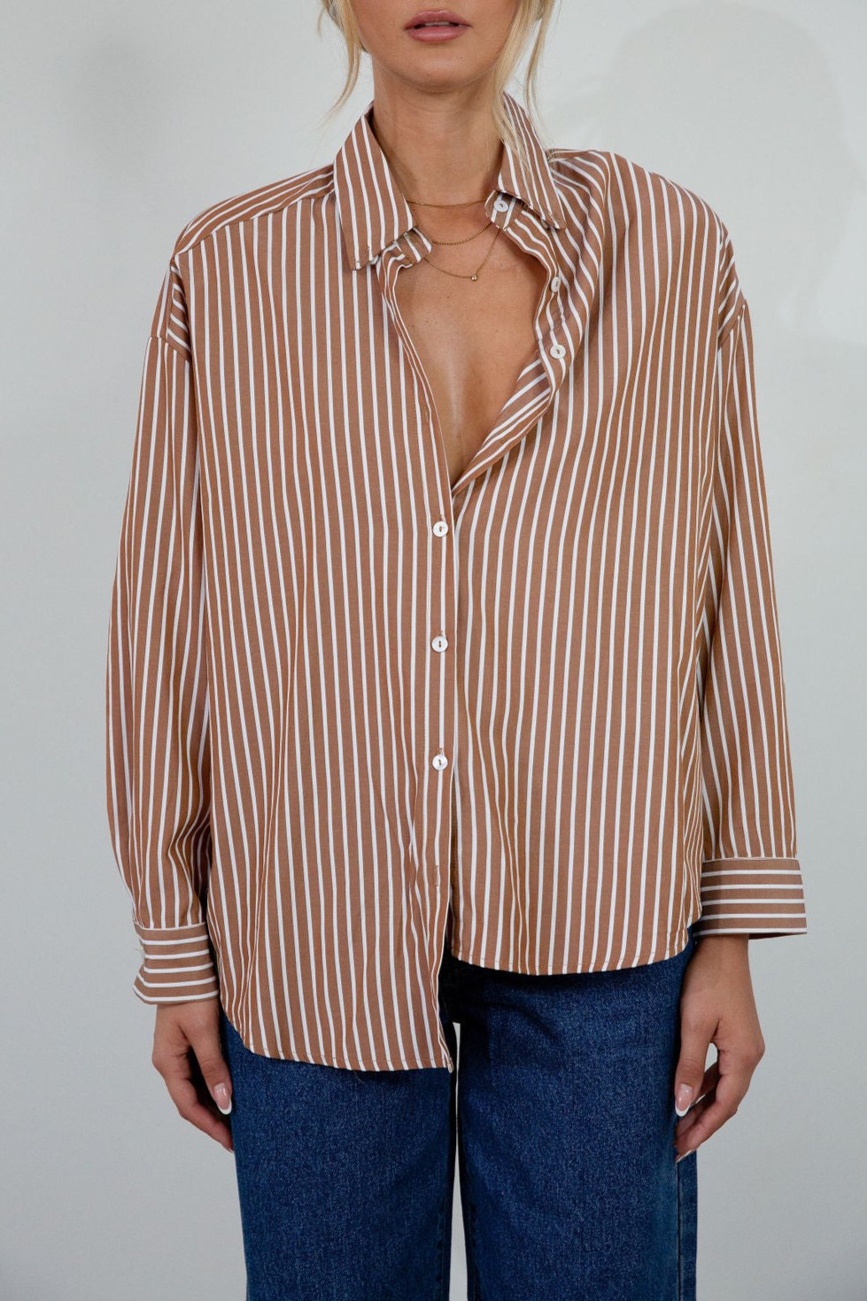 brown and white Striped woven shirt. Collar neckline. Long sleeves with button closures. Front button down closures. Unlined. oversized button down top