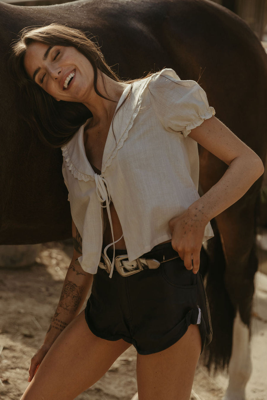 Woven top. Collar neckline. Short sleeves with elastic sleeve openings. Front tie closure. Unlined. coquette cream top