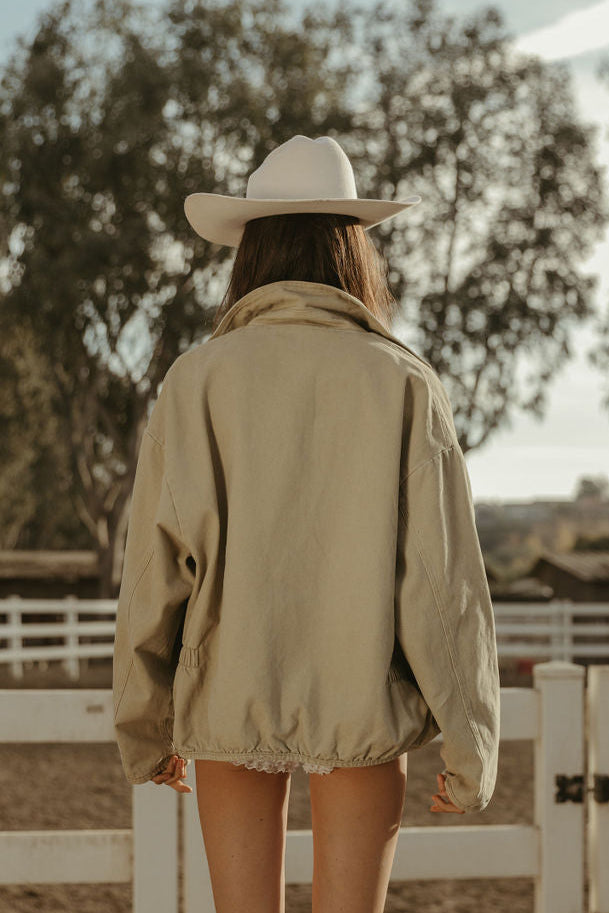 Denim jacket. Collar neckline. Long sleeves. Front zipper closure. Front pockets. Elastic sides. Fully lined. barn jacket. beige barn jacket. ranch shoot